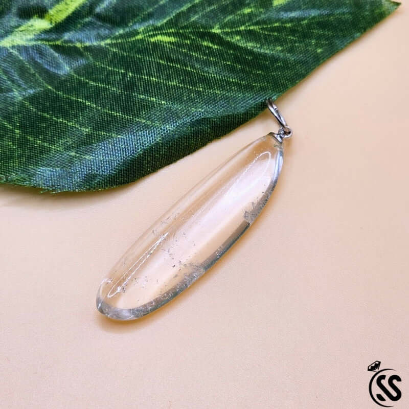 Clear Quartz Real Stone Pendant on green leaf, showcasing its natural clarity and energy-amplifying properties.