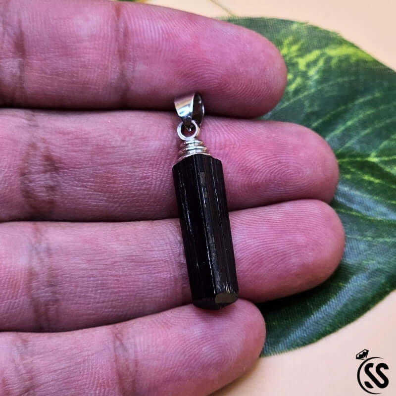 Black Tourmaline pendant in hand, showcasing natural stone for energy protection and grounding.