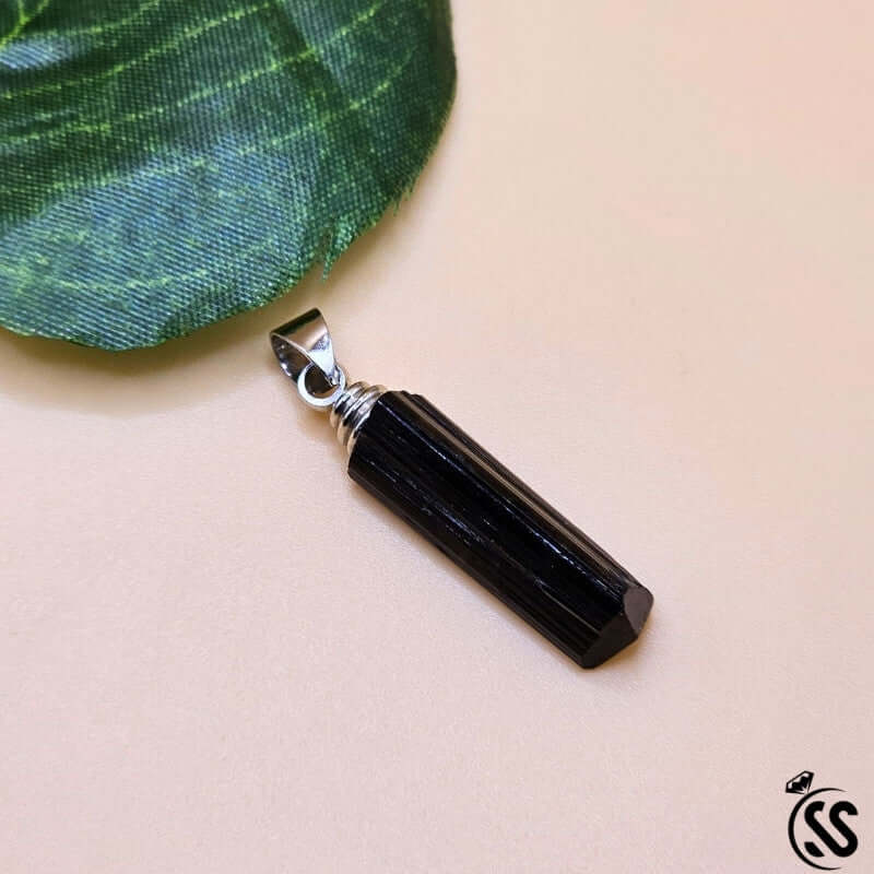 Black tourmaline real stone pendant on a light background, showcasing its natural, polished beauty.