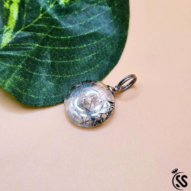Real Natural Muh-e-Najaf Stone Pendant on a green leaf, showcasing its crystal-clear elegance and spiritual essence.