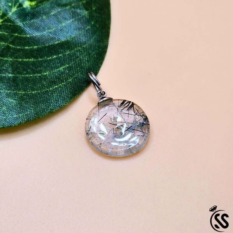 Real Natural Muh-e-Najaf Stone Pendant against a green leaf background, showcasing its crystal clarity and elegant design.