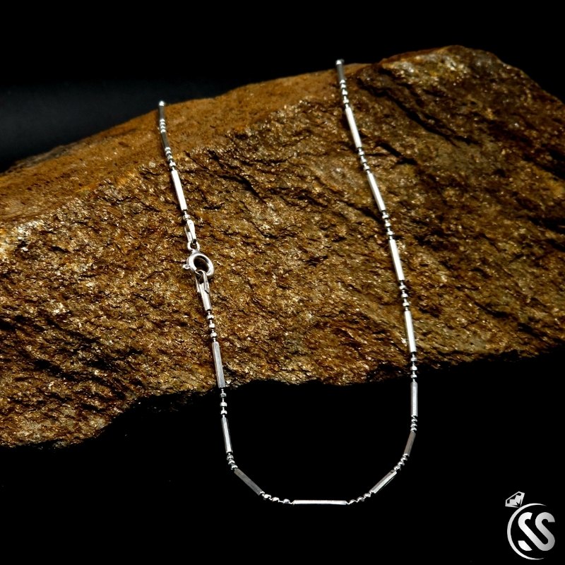 Italian Sterling Silver Ladies Chain resting on a textured brown stone background, showcasing elegance and timeless design.