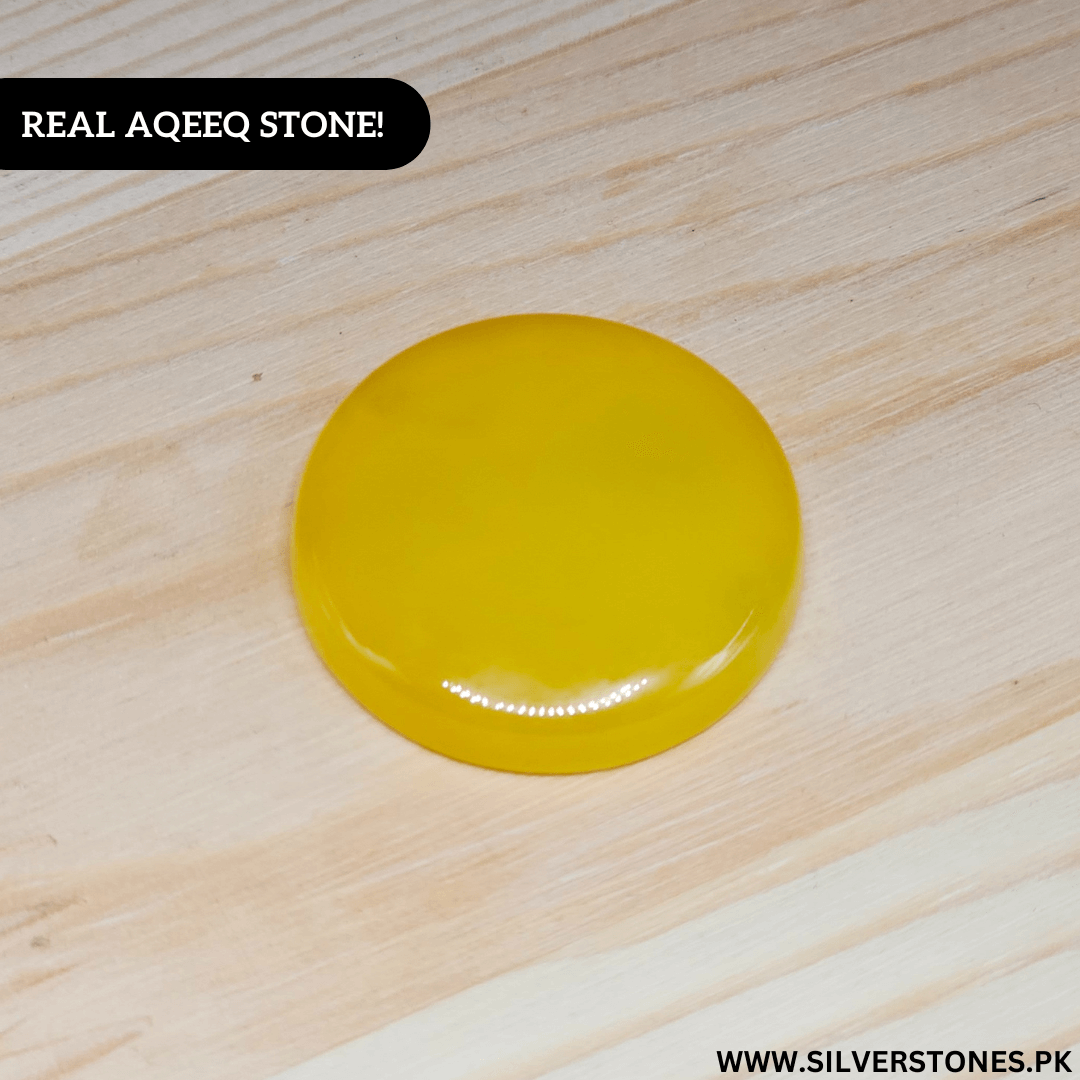 Real Yellow Aqeeq Yamni Stone in round shape, showcasing its vibrant golden hue on a wooden surface.