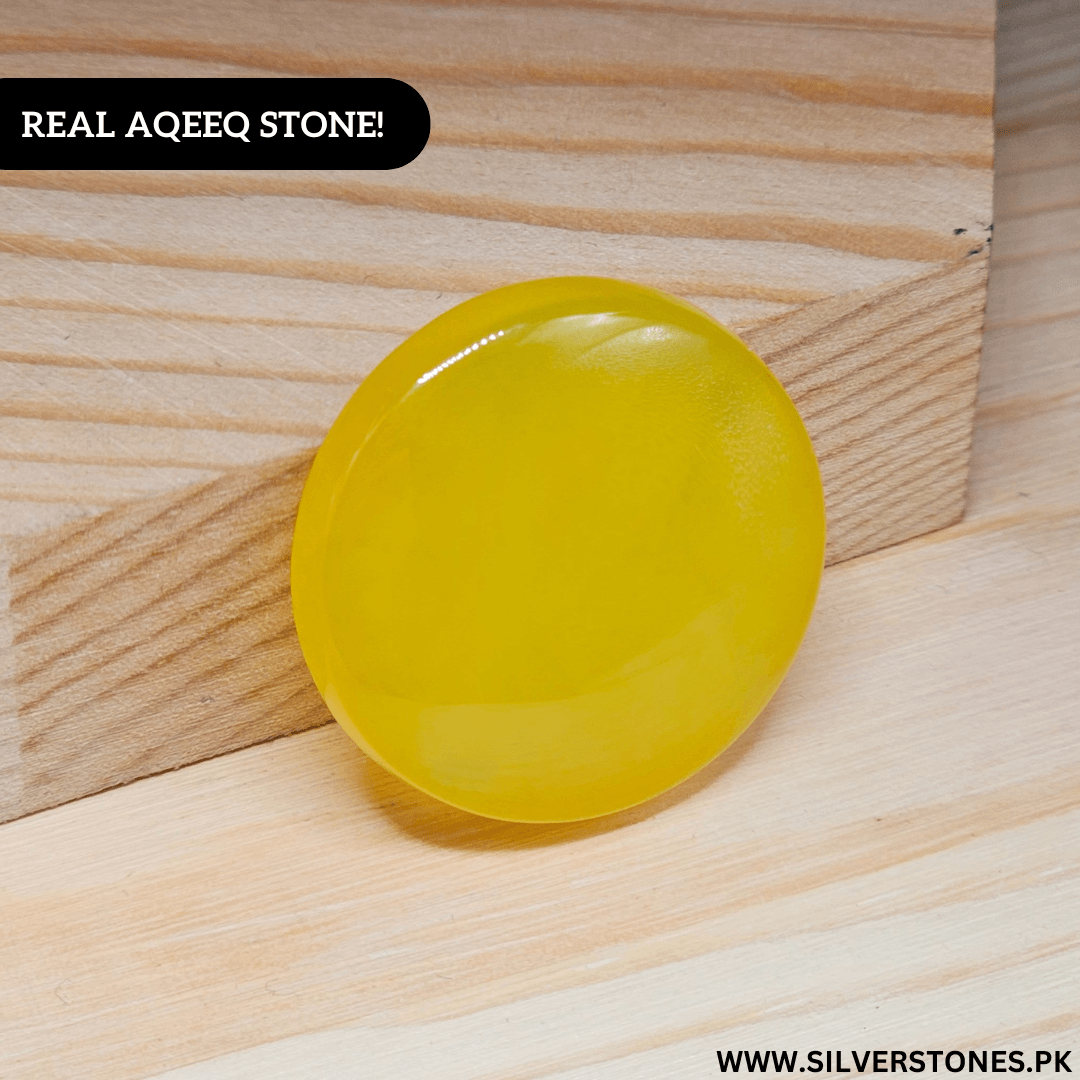 Real Yellow Aqeeq Yamni stone in round shape, showcasing its vibrant golden-yellow hue on a wooden background.