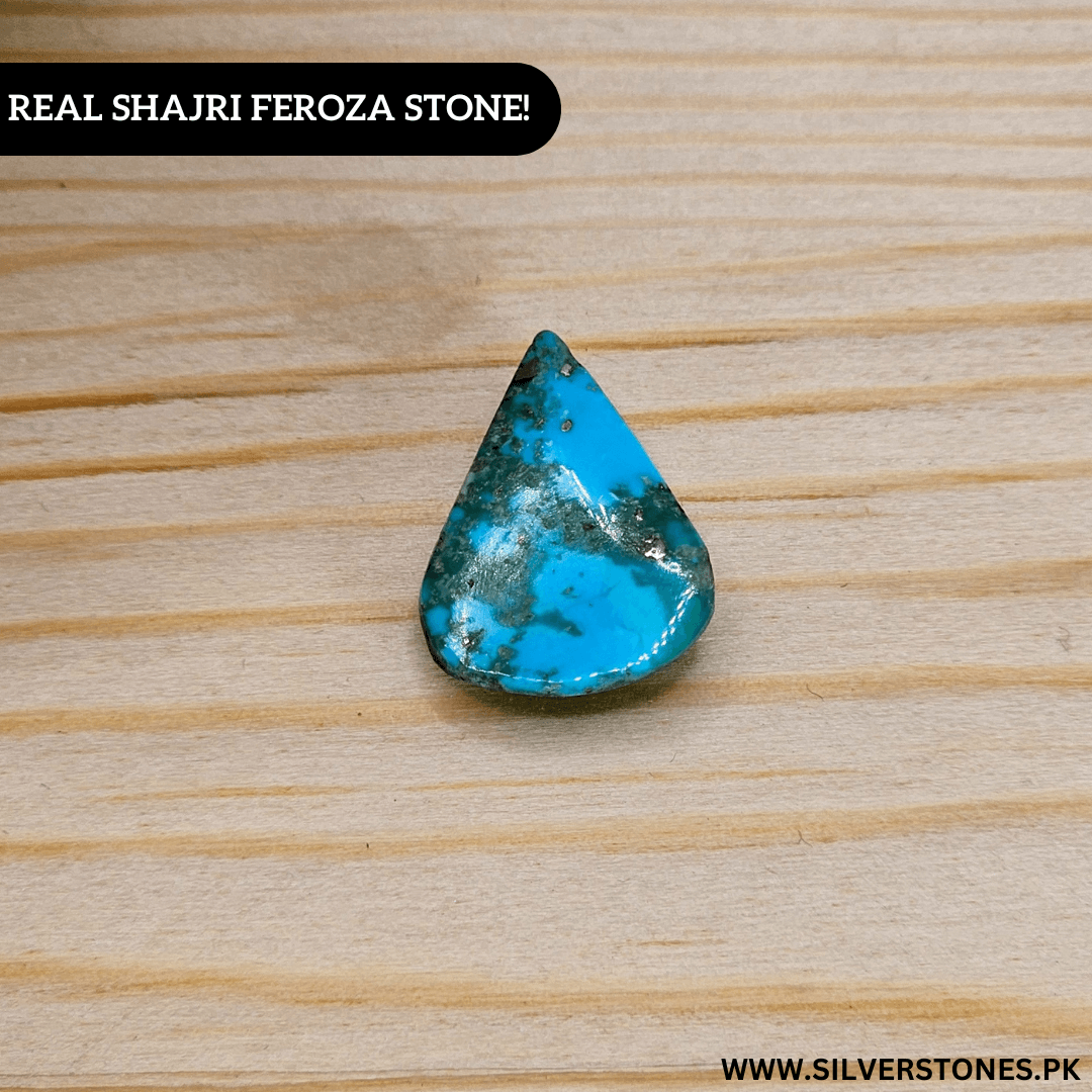 Real Shajri Irani Feroza stone in pear shape on wooden surface, showcasing its vibrant turquoise color and natural beauty.