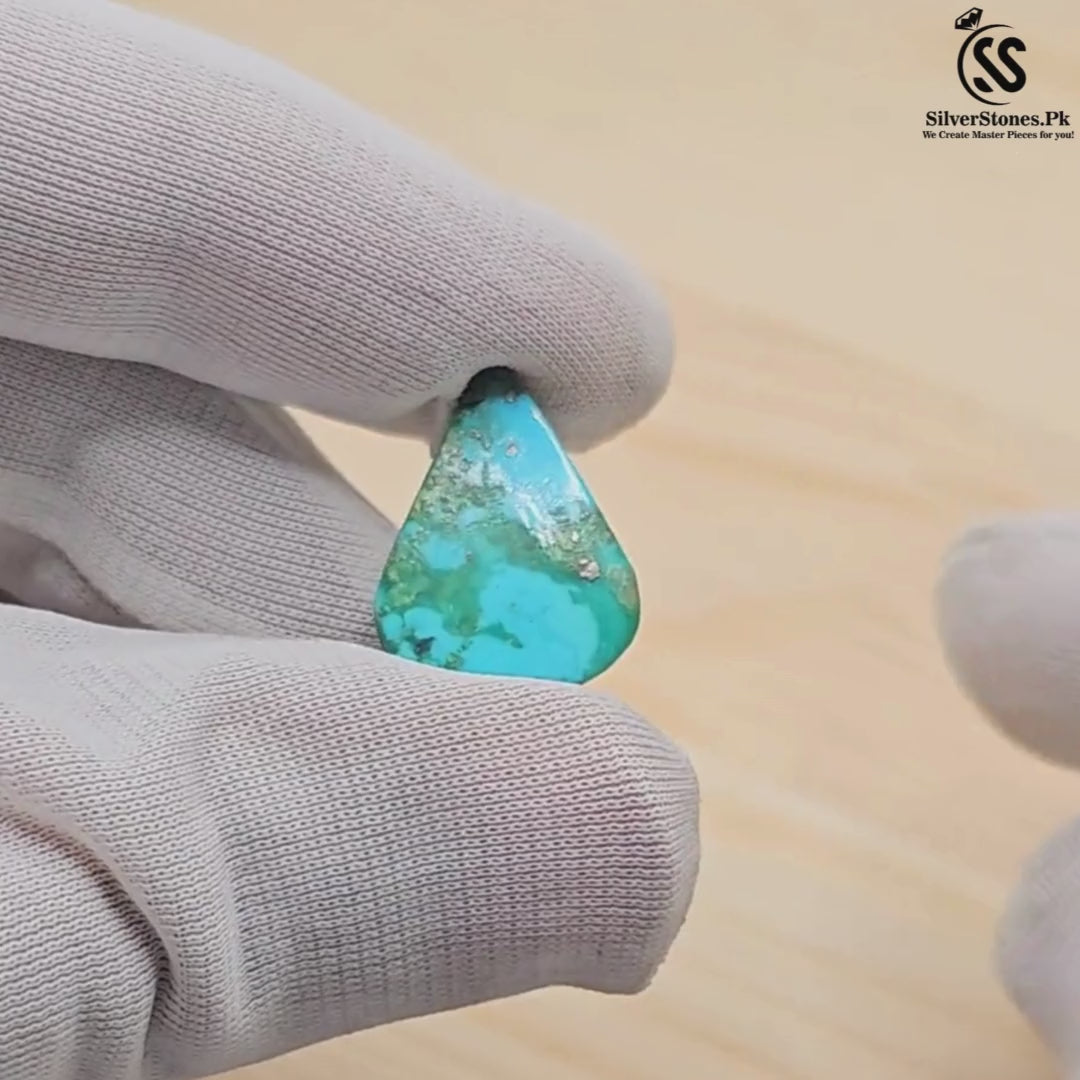 Real Shajri Irani Feroza stone in pear shape, held carefully, showcasing its vibrant turquoise hues.
