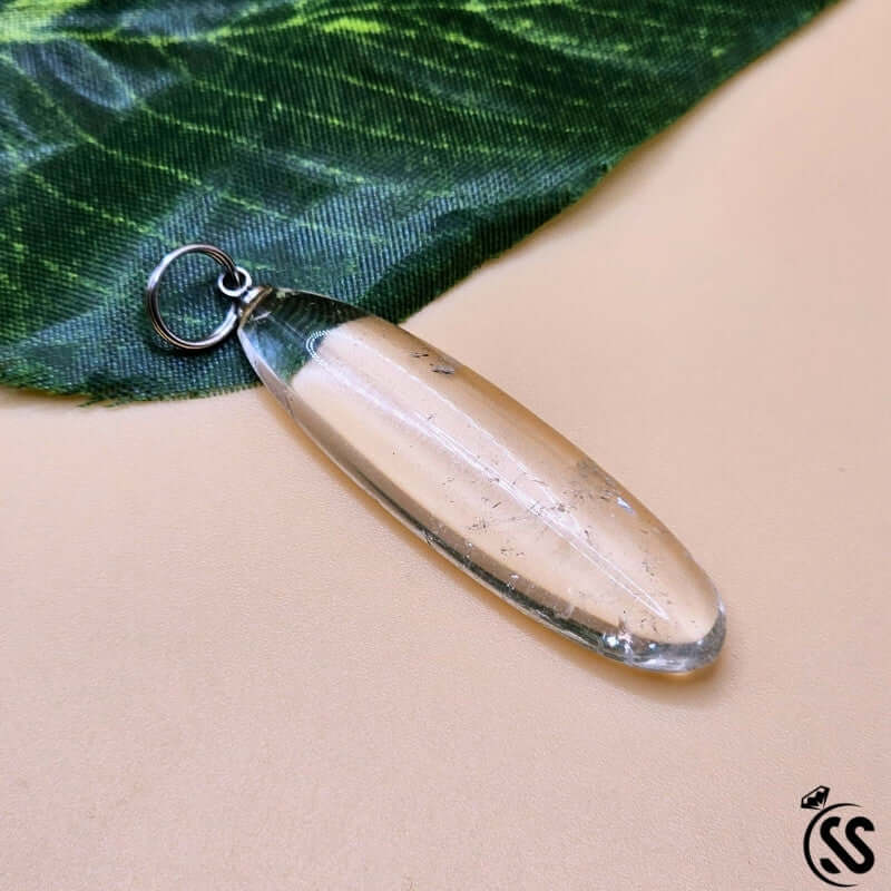 Clear Quartz Real Stone Pendant on green leaf, showcasing its natural beauty and healing properties.