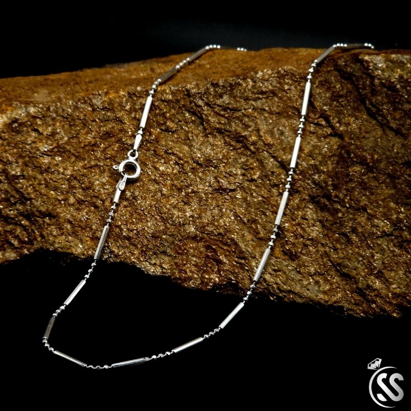 Italian sterling silver ladies chain laid on textured rock, showcasing its elegant design and clasp.