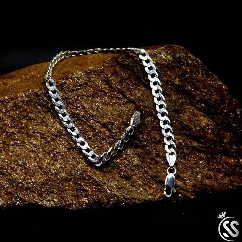 4mm Italian 925 sterling silver Cuban bracelet for men resting on textured stone.