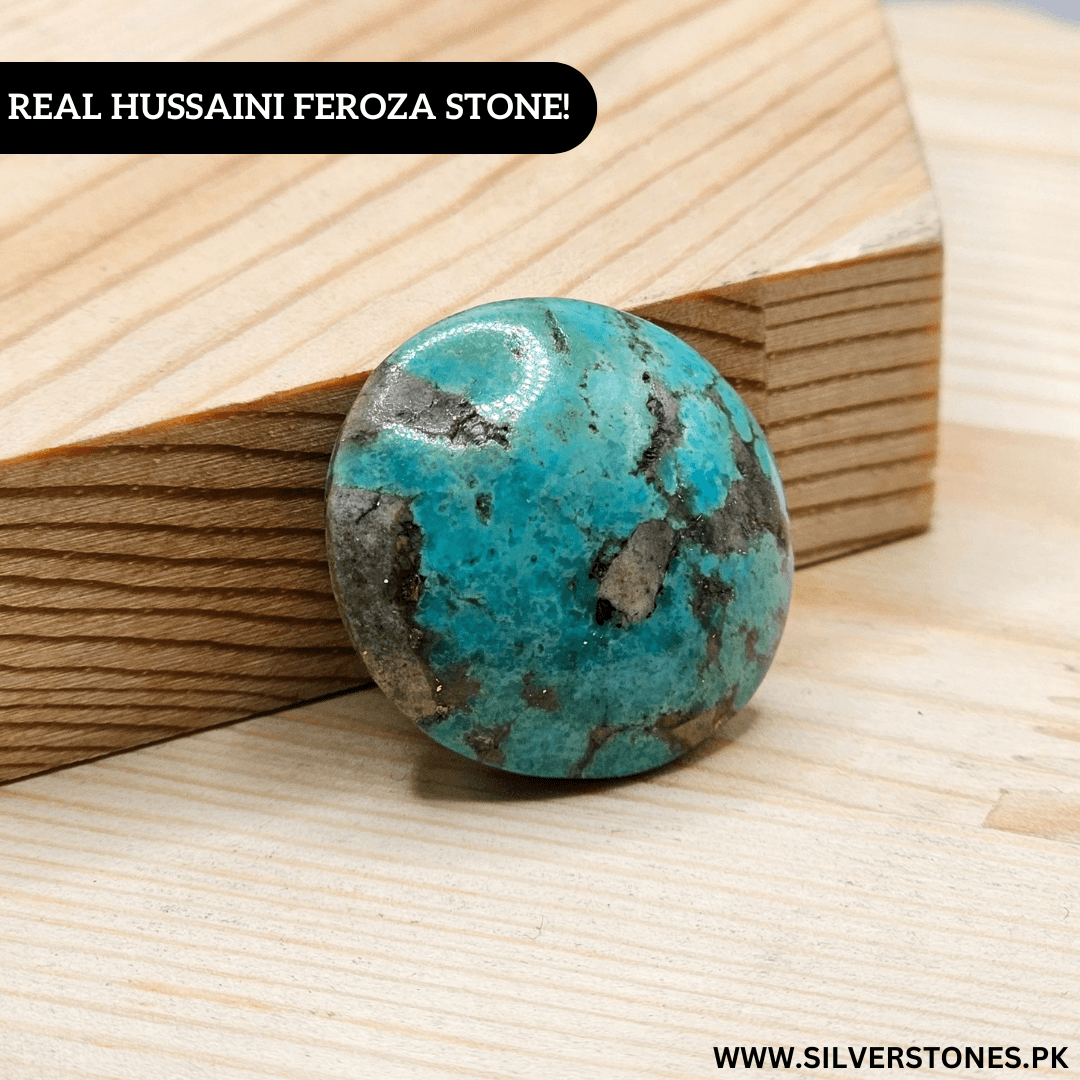 Real Shajri Hussaini Feroza stone with natural turquoise veins, round shape antique piece on wooden surface.