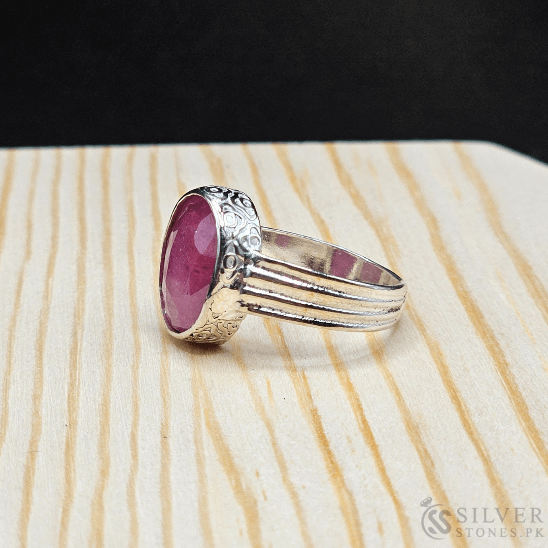 Handmade silver ring with an oval red ruby gemstone, showcasing intricate detailing and a unique design.