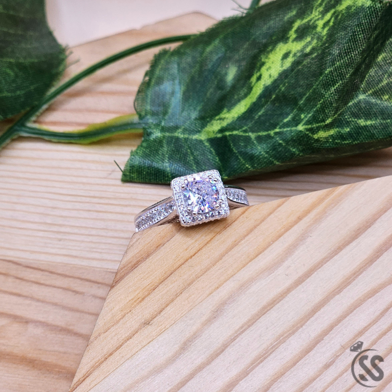925 Italian silver ladies ring with zircons on a wooden surface with leaves in the background.