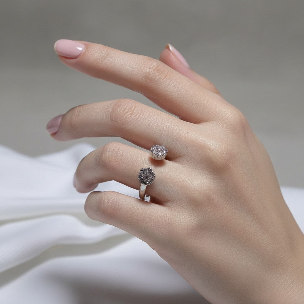 SilverStones.Pk adjustable ring with two flower-shaped zircon clusters, one pink and one grey, on white fabric.