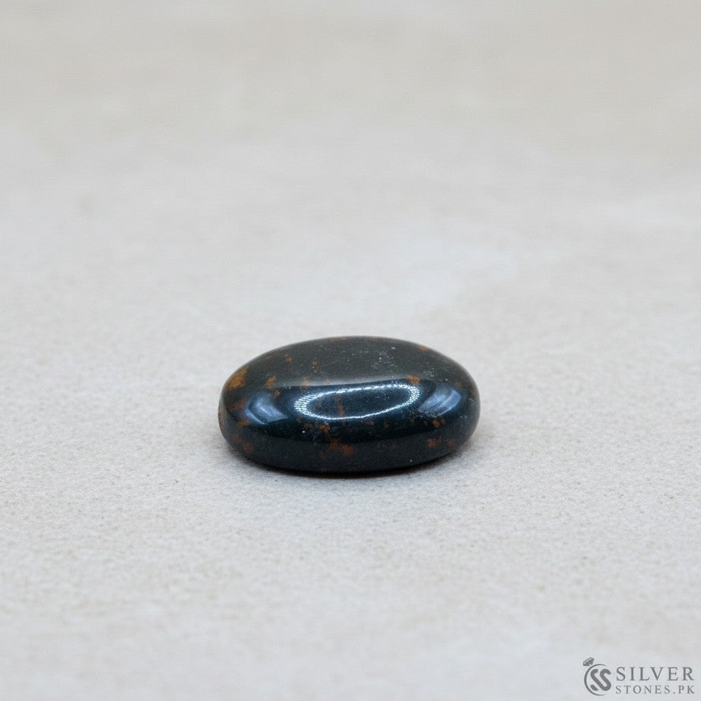 SilverStones.Pk oval bloodstone gemstone with red inclusions on a wooden display.