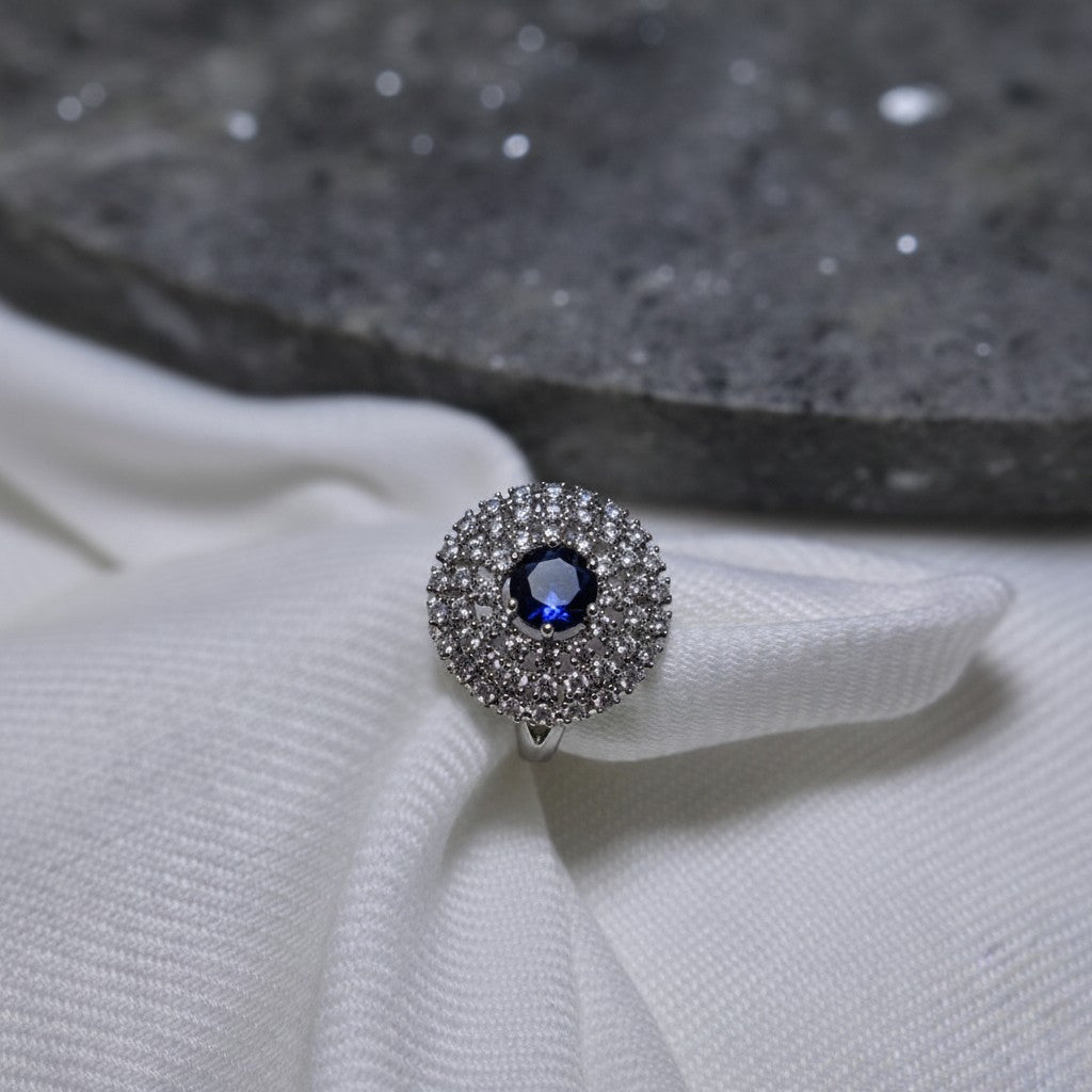 SilverStones.Pk A+ quality imitation ring with a central blue zircon stone surrounded by small clear zircon stones. Color silver.