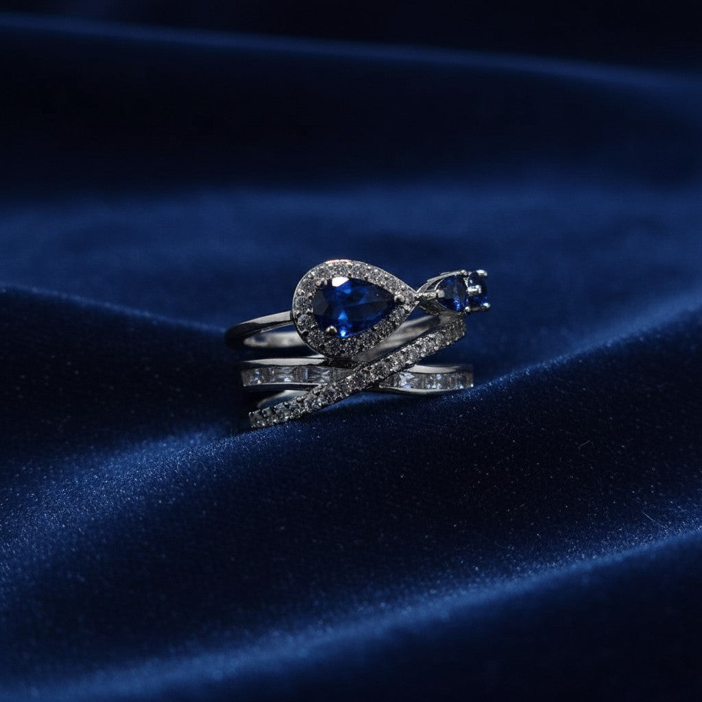 SilverStones.Pk ladies ring with pear-cut blue zircon and small square zircon, set in silver-tone metal with cubic zirconia accents.