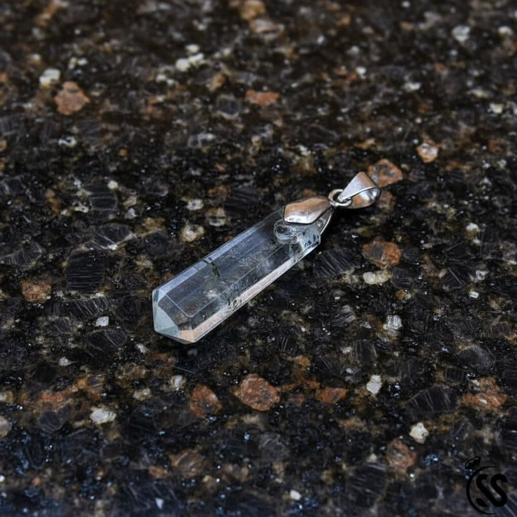 SilverStones.Pk clear fluorite crystal pendant with dark inclusions and silver-tone metal hook.