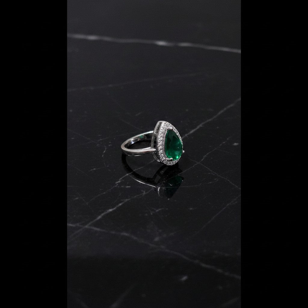 SilverStones.Pk pear-shaped emerald green zircon ring with halo of small clear stones.