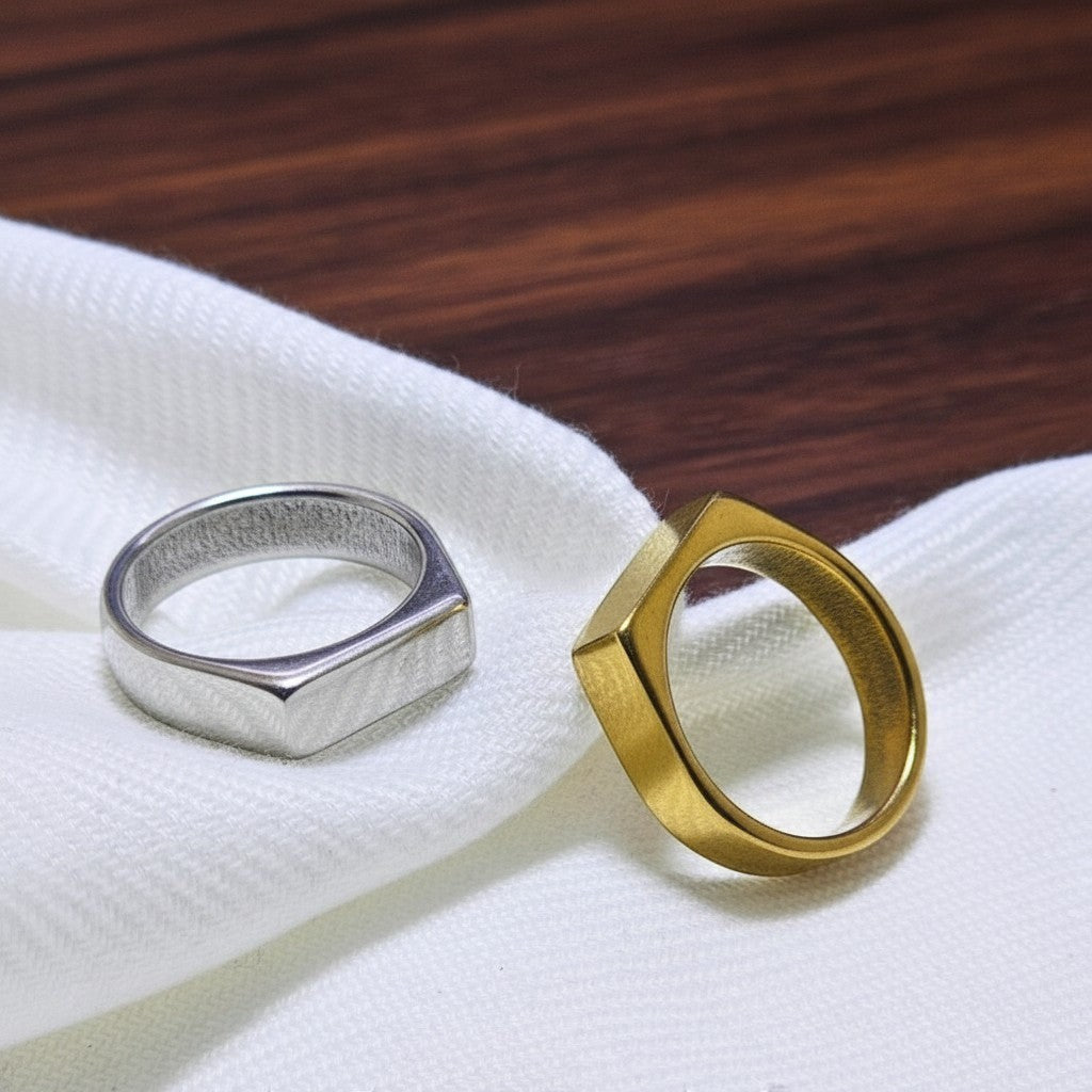 SilverStones.Pk pair of imitation ring bands, one silver, one gold, with simple geometric designs.