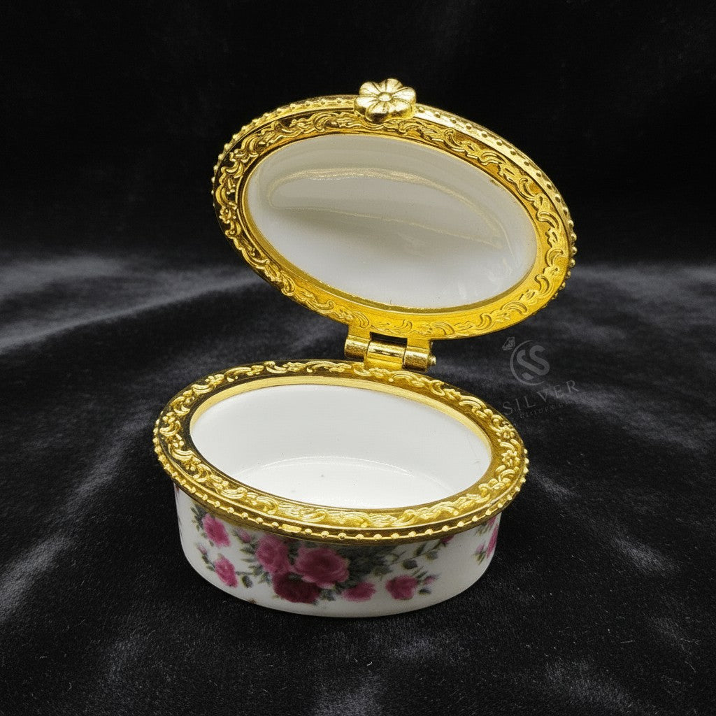 SilverStones.Pk ornate oval jewelry box with floral design and gold trim. White interior with velvet lining.
