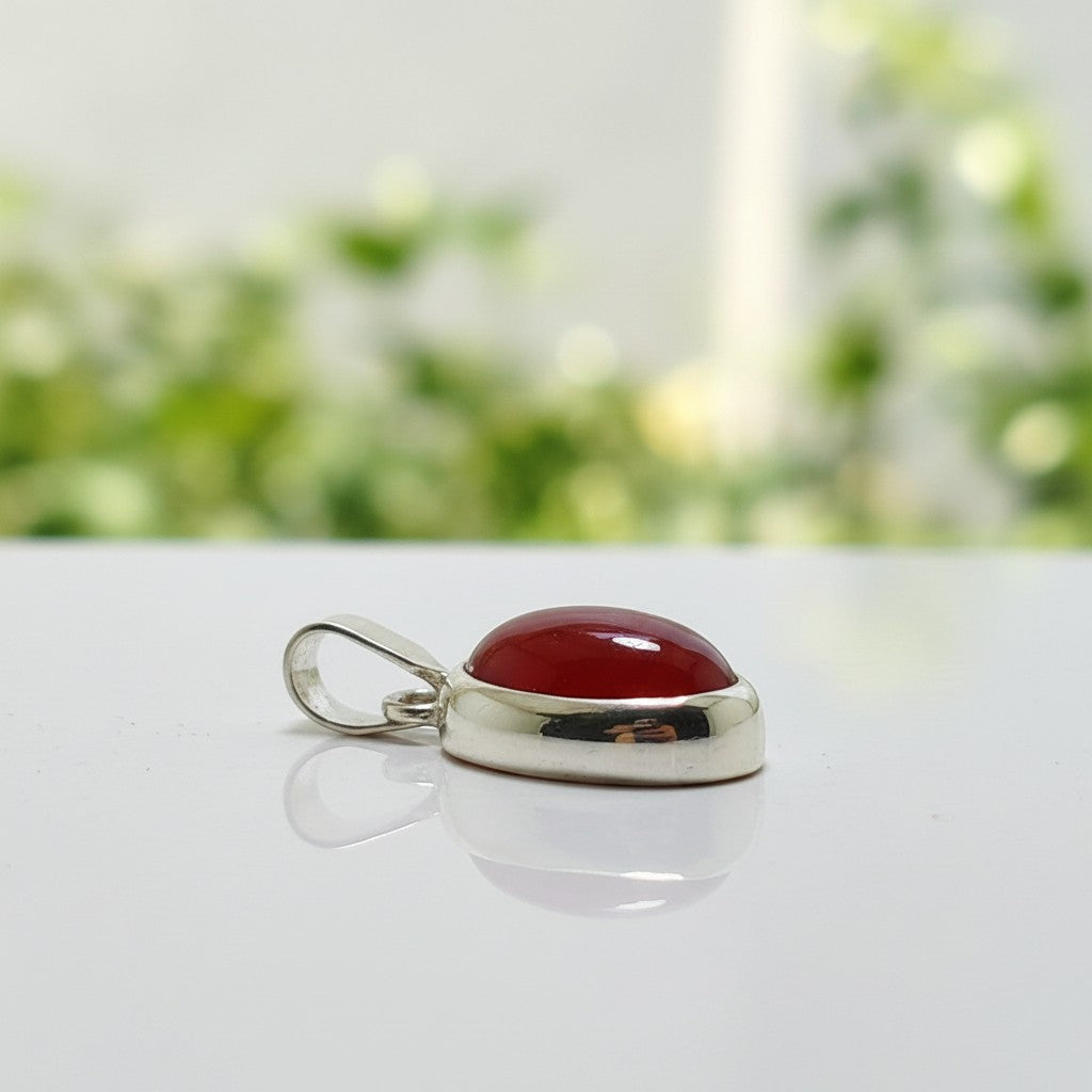 SilverStones.Pk oval red aqeeq gemstone pendant set in sterling silver. Features a smooth, polished cabochon cut stone.