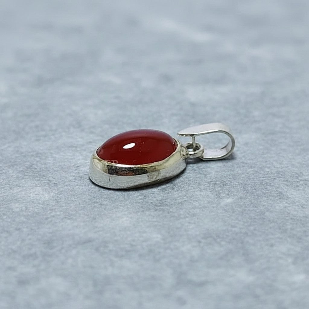 SilverStones.Pk oval red aqeeq gemstone pendant with a silver bail. The stone is smooth and polished.
