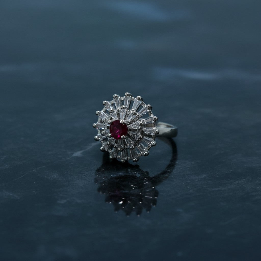 SilverStones.Pk imitation ring with a central red zircon stone surrounded by baguette-cut clear zircon stones, set in silver-tone metal.