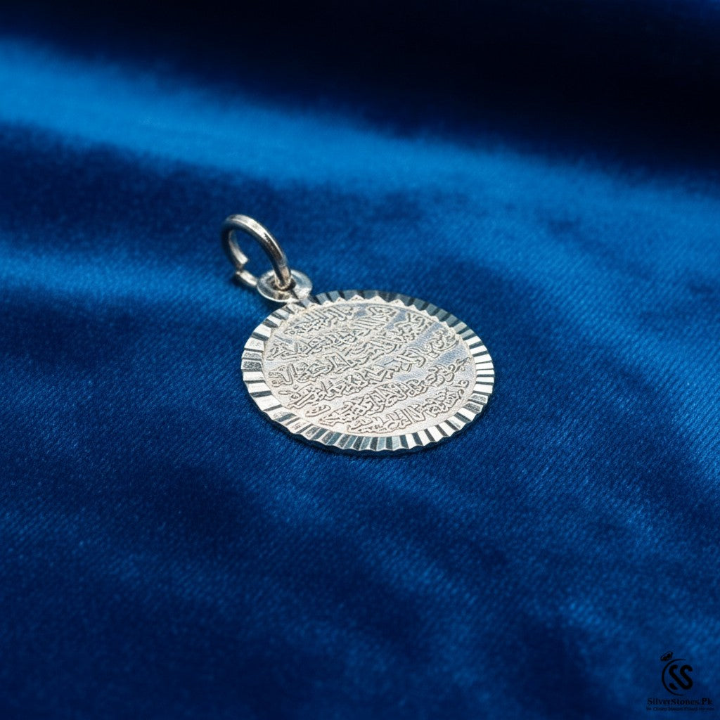 SilverStones.Pk silver Ayat ul Kursi pendant with intricate Arabic calligraphy and a textured edge on a blue background.
