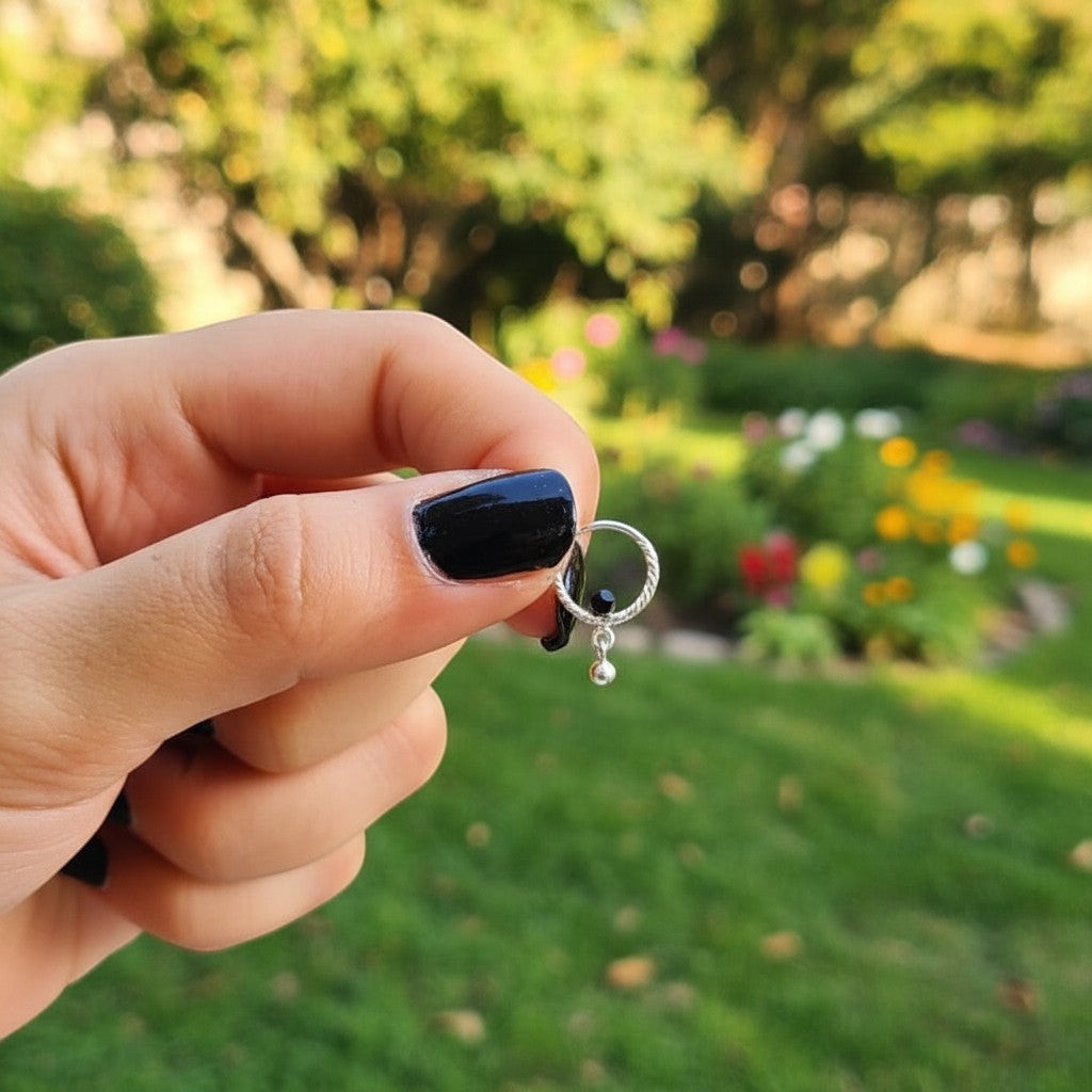 SilverStones.Pk delicate silver nose ring with a twisted hoop and a small dangling charm, featuring a sparkling zircon.