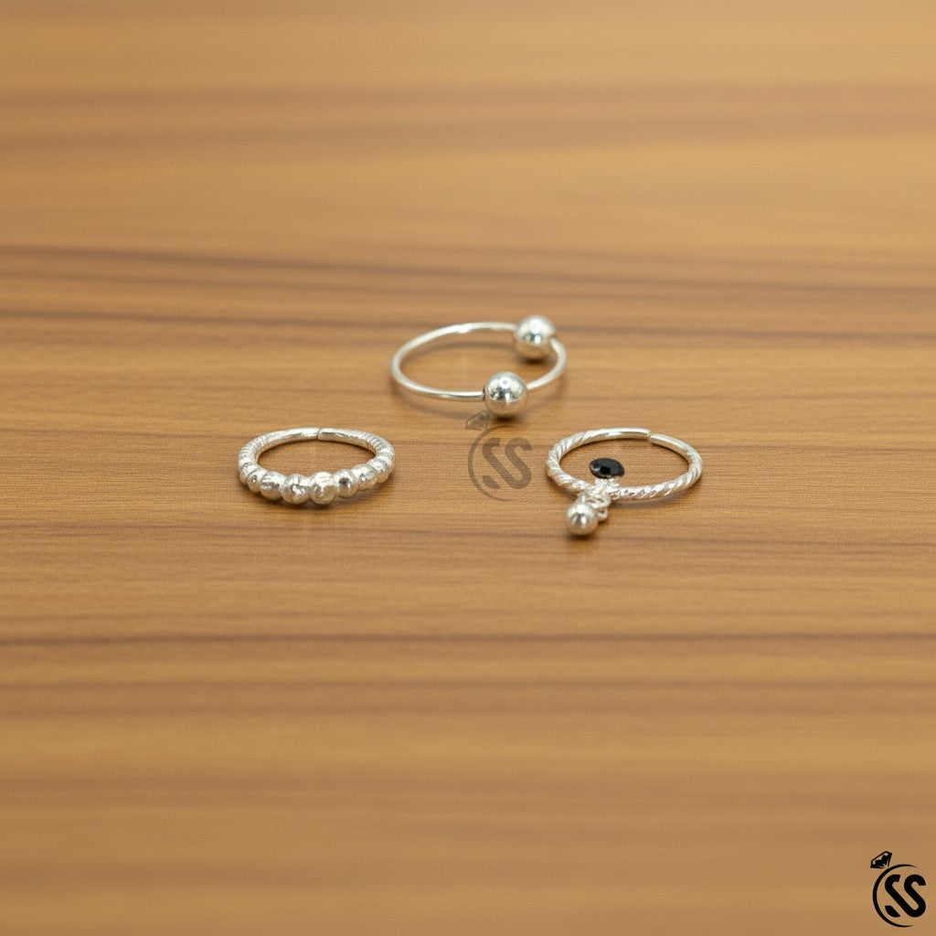 SilverStones.Pk pack of 3 silver nose rings, one with a ball end, one with beaded detail, and one with a twisted design and black zircon.