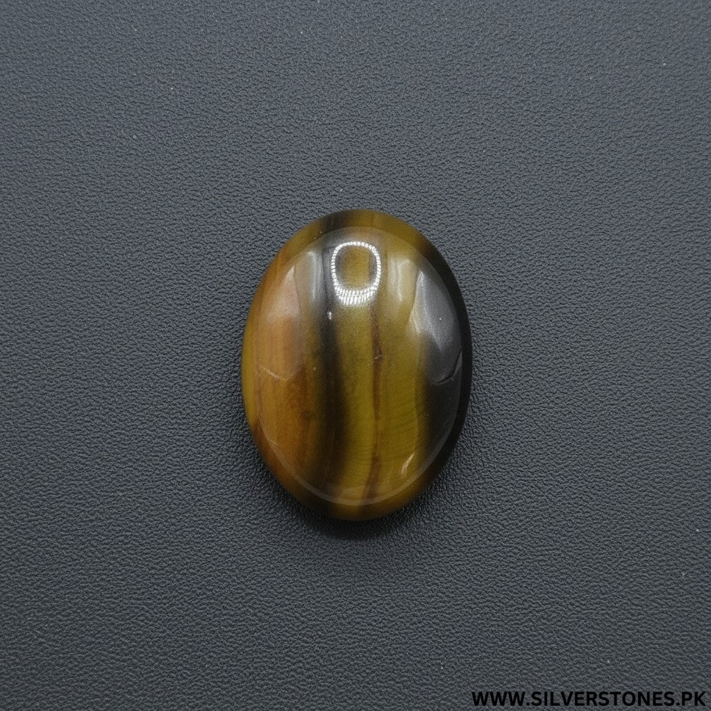 SilverStones.Pk oval Sulemani Aqeeq stone with natural brown and yellow banding, set against a light wood background.