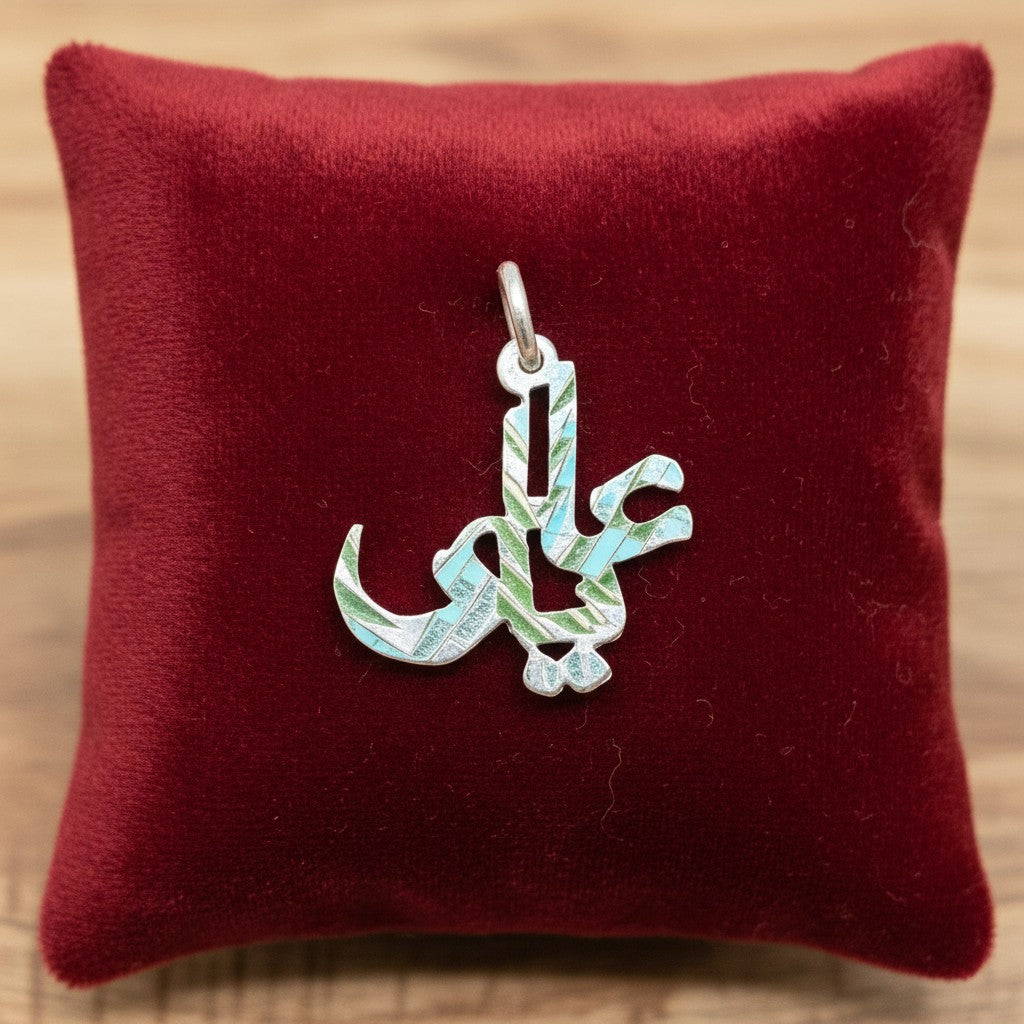 SilverStones.Pk Ya Ali pendant in sterling silver with Arabic calligraphy, set against a green grass background.