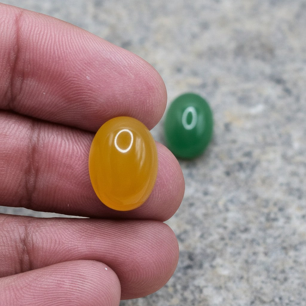 SilverStones.Pk real Yamni Aqeeq stones, one yellow oval cabochon and one green oval cabochon, held by fingers.